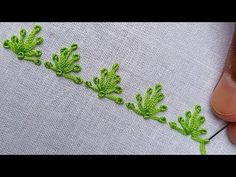 someone is stitching green leaves on a piece of fabric