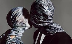 two people wearing black and white clothing with their heads wrapped in plastic wraps looking at each other