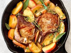 pork chops and apples in a cast iron skillet on a white countertop