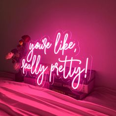 a pink neon sign that says you're like really pretty on top of a bed