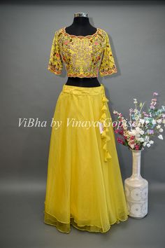 The Yellow Lehenga combines traditional elements with modern design. The beautifully embroidered blouse adds a touch of elegance, while the detachable draped saree dupatta offers versatility and convenience. With delicate ruffles along the end, this lehenga is perfect for any special occasion and Haldi events.. Organza Blouse With Cutdana For Reception, Organza Blouse Piece For Reception, Transitional Organza Blouse Piece For Reception, Transitional Georgette Lehenga With Floral Embroidery, Festive Embroidered Top For Reception With Traditional Drape, Festive Embroidered Top For Reception, Organza Blouse Piece With Floral Embroidery For Reception, Festive Organza Blouse With Floral Embroidery, Designer Organza Blouse With Floral Embroidery