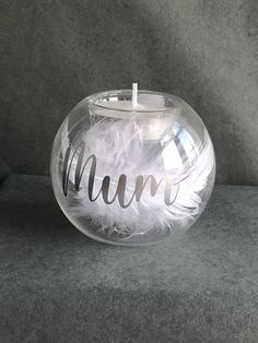 a clear glass candle holder with the word mum written in cursive writing on it