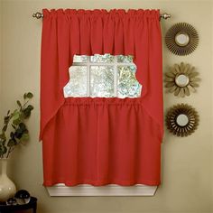 a red curtain hanging on the side of a window next to a potted plant