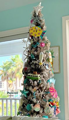 a decorated christmas tree in the corner of a room with blue walls and white trim