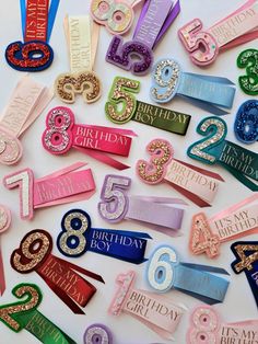 a bunch of different colored birthday badges on a white surface with the number twenty five