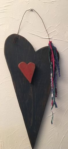 a wooden heart hanging on the wall with some string attached to it's side