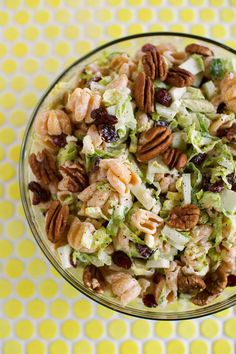 a bowl filled with salad and nuts on top of a yellow and white tablecloth