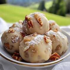 a white plate topped with donuts covered in icing and pecans on top of a table