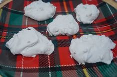 four cookies covered in white icing sitting on a plaid plate