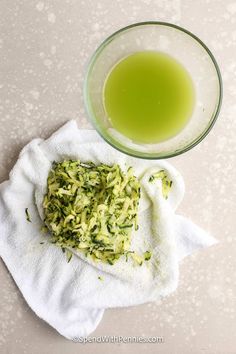 a glass bowl filled with green liquid next to a towel on top of a table