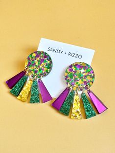 Purple, green, and gold glitter acrylic topper with dangles of mirrored purple, green glitter, and gold glitter. The perfect earring to celebrate Mardi Gras! *Hypoallergenic and nickel free. Purple Resin Jewelry For Party, Purple Resin Party Jewelry, Purple Glitter Party Jewelry, Green Jewelry For Mardi Gras Party, Fun Purple Earrings For Party, Fun Resin Jewelry For Party, Fun Resin Jewelry For Parties, Fun Resin Party Jewelry, Green Sparkling Jewelry For Party