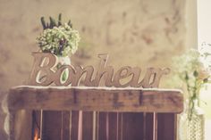 a wooden sign that says bonhear sitting on top of a table next to flowers