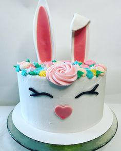 a white cake with pink frosting and bunny ears