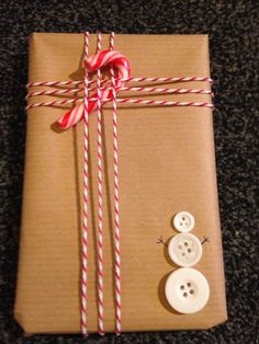 a present wrapped in brown paper with red and white striped ribbon, two buttons on each side