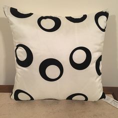 a white pillow with black circles on it sitting on the floor next to a wall