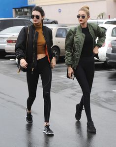 two women walking down the street in black leggings and jackets, both wearing sunglasses