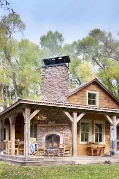 a painting of a log cabin with an outdoor fireplace and covered patio area in the foreground