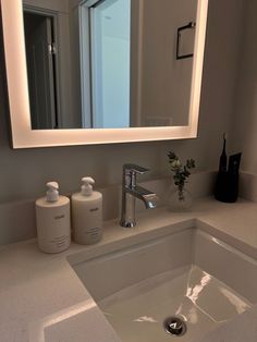 a bathroom sink with soap and lotion in front of a large mirror above it