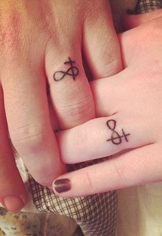 two people holding hands with tattoos on their fingers