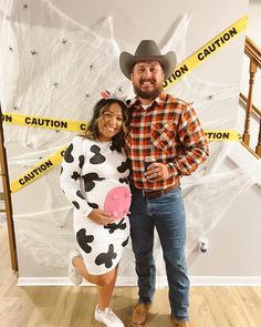 a man and woman dressed up as cowgirl and cowboy with caution tape on the wall behind them