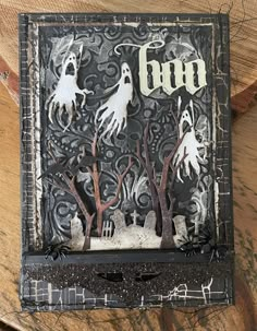 an altered halloween card with the word boo on it and ghost hands coming out from trees