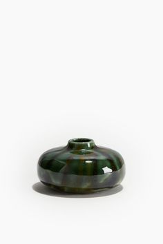 a green vase sitting on top of a white table