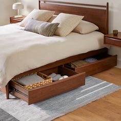 a bed with two drawers underneath it on a rug next to a table and lamp