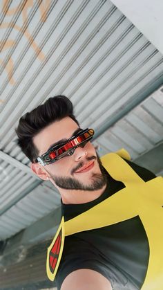 a man with sunglasses on his face wearing a yellow and black shirt under a metal structure