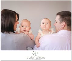 a man and woman holding a baby in front of a white wall with the caption crystal star photography