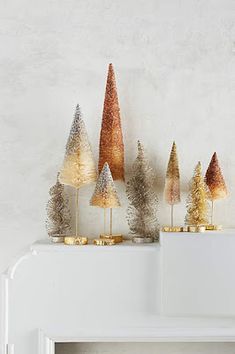 five small trees are lined up on top of each other in gold, silver and white