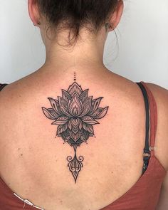 the back of a woman's neck with a lotus tattoo on her left shoulder