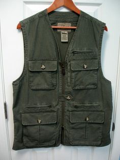 A fantastic hiking vest from L.L. Bean. Men's roomy medium. Army green. I bought this but do not remember wearing it. Looks new. It's been hanging in closet for years. It is a very well made vest with 11 pockets throughout. If you need pockets this is the vest for you. Would be perfect for photographers. Has a nice leather zipper pull. The inside is mesh lined. This is a thicker cotton and perfect for fall or winter. Waist has 2 buttons to tighten if needed. This vest will last for many many yea Practical Outerwear With Pockets For Camping, Practical Camping Outerwear With Pockets, Military Style Khaki Vest For Outdoor Activities, Khaki Military Vest For Outdoor Activities, Casual Hiking Vest With Cargo Pockets, Casual Green Vest With Pockets, Green Casual Vest With Pockets, Utility Vest With Multiple Pockets For Outdoor, Casual Adventure Vest With Multiple Pockets