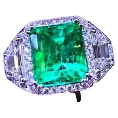 An exceptional ring , in gorgeous design, so sophisticated, elegant , a very glamor style by Italian jewelry designer. Ring come in 18k gold with Natural Colombian Emerald of ct 6,00 carats, extra fine quality, and two trapeze cut diamonds of 1, 00 carats, G-H / VS , and round brilliant cut diamonds 1,90 F/VS. Handcrafted by artisan goldsmith. .Excellent manufacturer and quality of stones . Complete with AIG report. Whosale price . Note: on my shipment, no taxes. Formal Elegant Gia Certified Emerald Ring, Luxury Green Diamond Ring For Formal Occasions, Formal Green Diamond Ring, Luxury Hallmarked Emerald Ring For Formal Occasions, Elegant Hallmarked Baguette Cut Emerald Ring, Elegant Formal Emerald Ring, Luxury Emerald Cut Cluster Ring For Formal Events, Luxury Green Cluster Ring For Formal Occasions, Luxury Green Cluster Ring For Formal Events