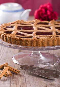 a pie sitting on top of a wooden table next to a glass plate with cinnamon sticks