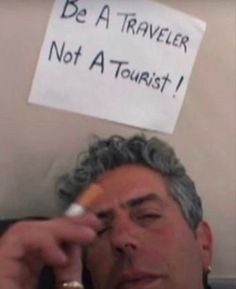 a man holding a toothbrush in front of his face with a sign on the wall behind him