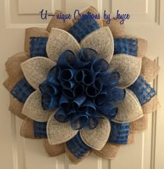 a burlap and blue flower is hanging on the front door