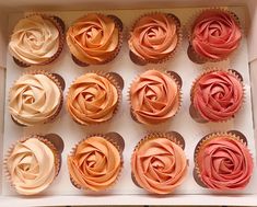 twelve cupcakes with pink and orange frosting in a box