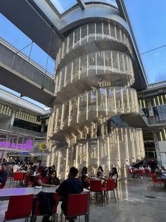 people are sitting at tables in the middle of a large building with lights on it