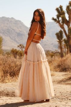 a woman standing in the desert wearing a dress