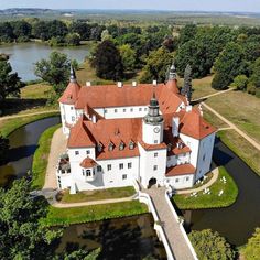 an aerial view of a large white castle with red roof and two towers, surrounded by trees