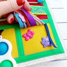 a hand is holding onto some colorful bracelets on a piece of cloth with scissors