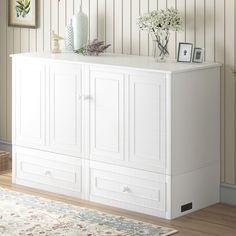 a white cabinet with drawers and vases on top of it in a living room