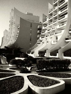 black and white photograph of modern architecture in front of an apartment building with curved balconies