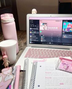 an open laptop computer sitting on top of a desk next to a cup and toy