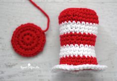 a red and white crocheted hat next to a small object on a table