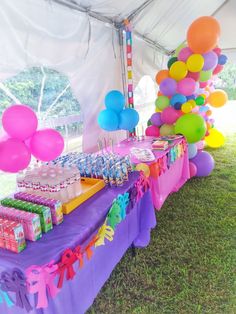 the table is set up with balloons and confetti for an outdoor birthday party