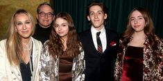 a group of people standing next to each other in front of a green curtained wall