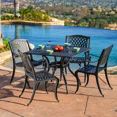 an outdoor table with four chairs next to a pool