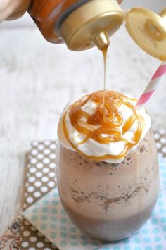 someone pouring caramel sauce on top of a chocolate milkshake