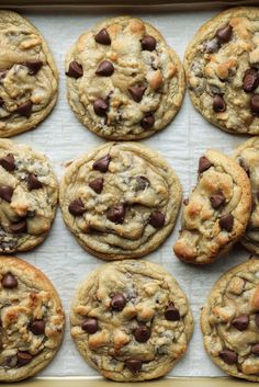 chocolate chip cookies are lined up on a baking sheet